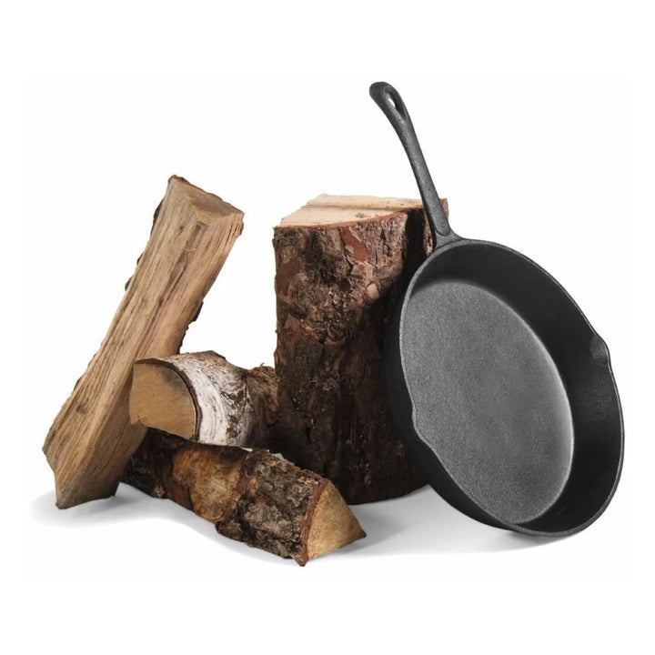 Gusseisenpfanne – Pfanne mit sichtbarer Innenseite an Holzscheiten angelehnt