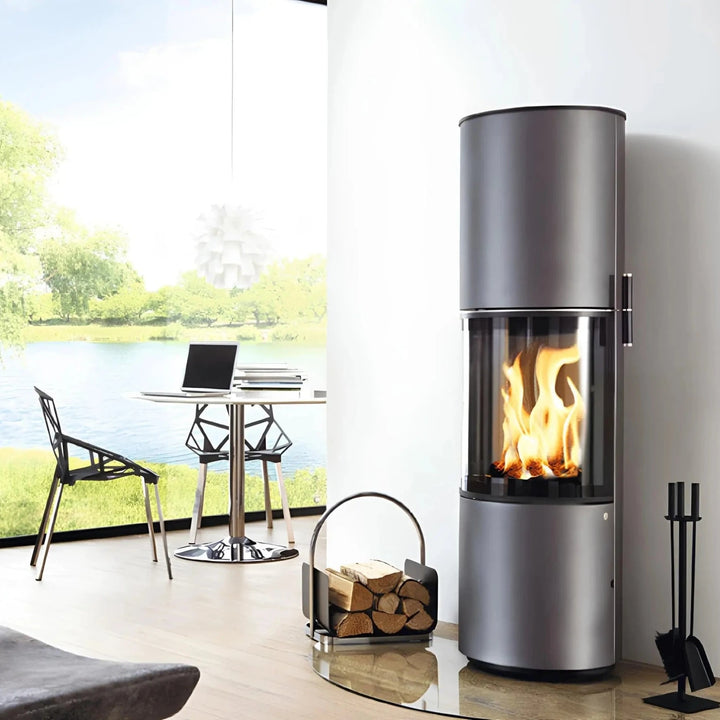 Kaminofen CERA DESIGN Volare | 6 kW – Runder grauer Kaminofen neben einer Sitzgruppe im hellen Wohnraum