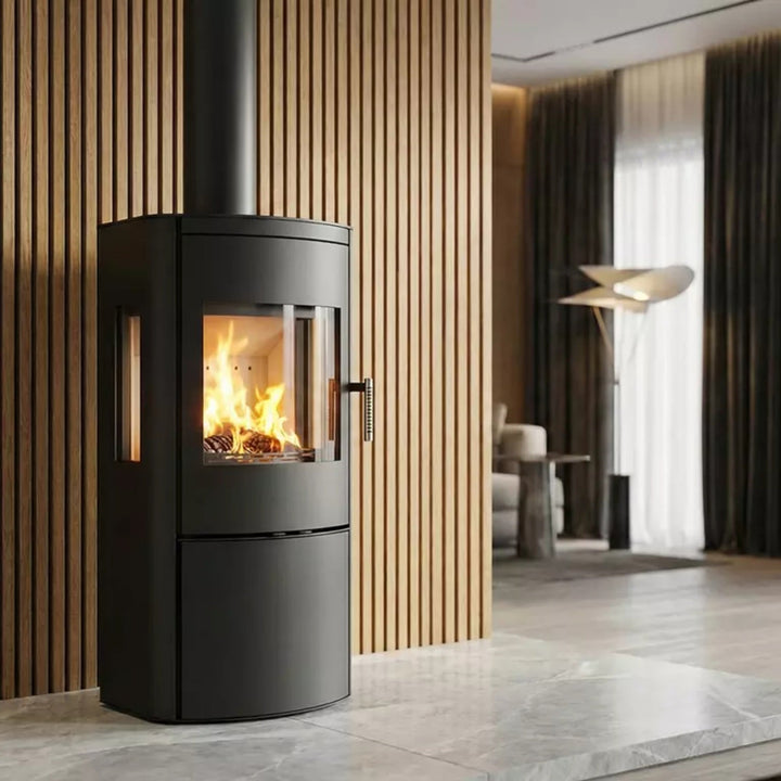 Kaminofen Hitze REGO 3S 5 kW – Brennender Kaminofen vor einer Holzwand