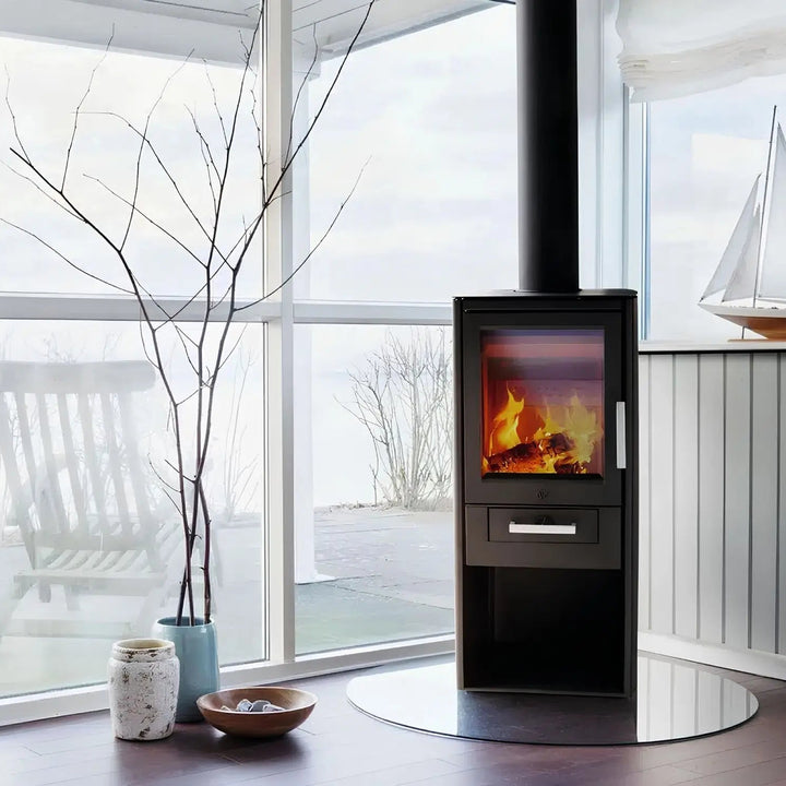 Kaminofen Varde Ovne Als 5 kW – Kaminofen mit Feuer und Rauchrohr vor einer Fensterfront