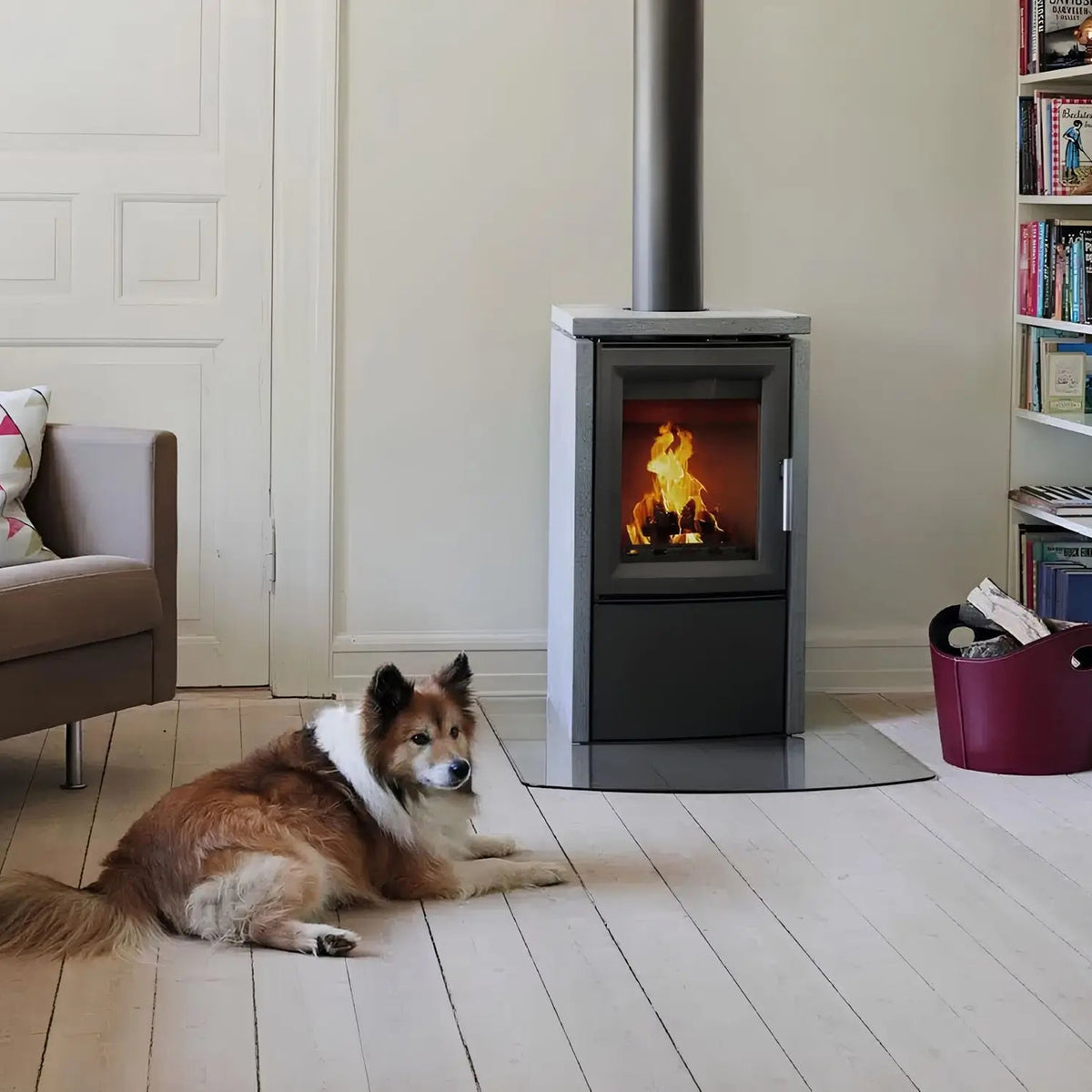 Kaminofen Varde Ovne Aura 3 Naturstein 5 kW – Kaminofen mit Feuer im Wohnraum mit liegendem Hund Kaminofen Varde Ovne Aura 3 Naturstein 5 kW – Kaminofen mit Feuer im Wohnraum mit liegendem Hund