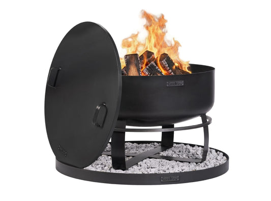 „Schwarze XXL-Feuerschale Viking mit brennendem Holzfeuer, passendem Stahldeckel und dekorativer runder Basis, die mit hellen Ziersteinen gefüllt ist.“
