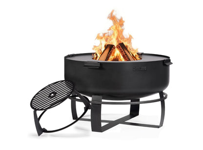 Brennende XXL-Feuerschale Viking aus schwarzem Stahl mit aufgelegter Grillplatte und daneben stehendem erhöhtem Grillrost-Aufsatz.