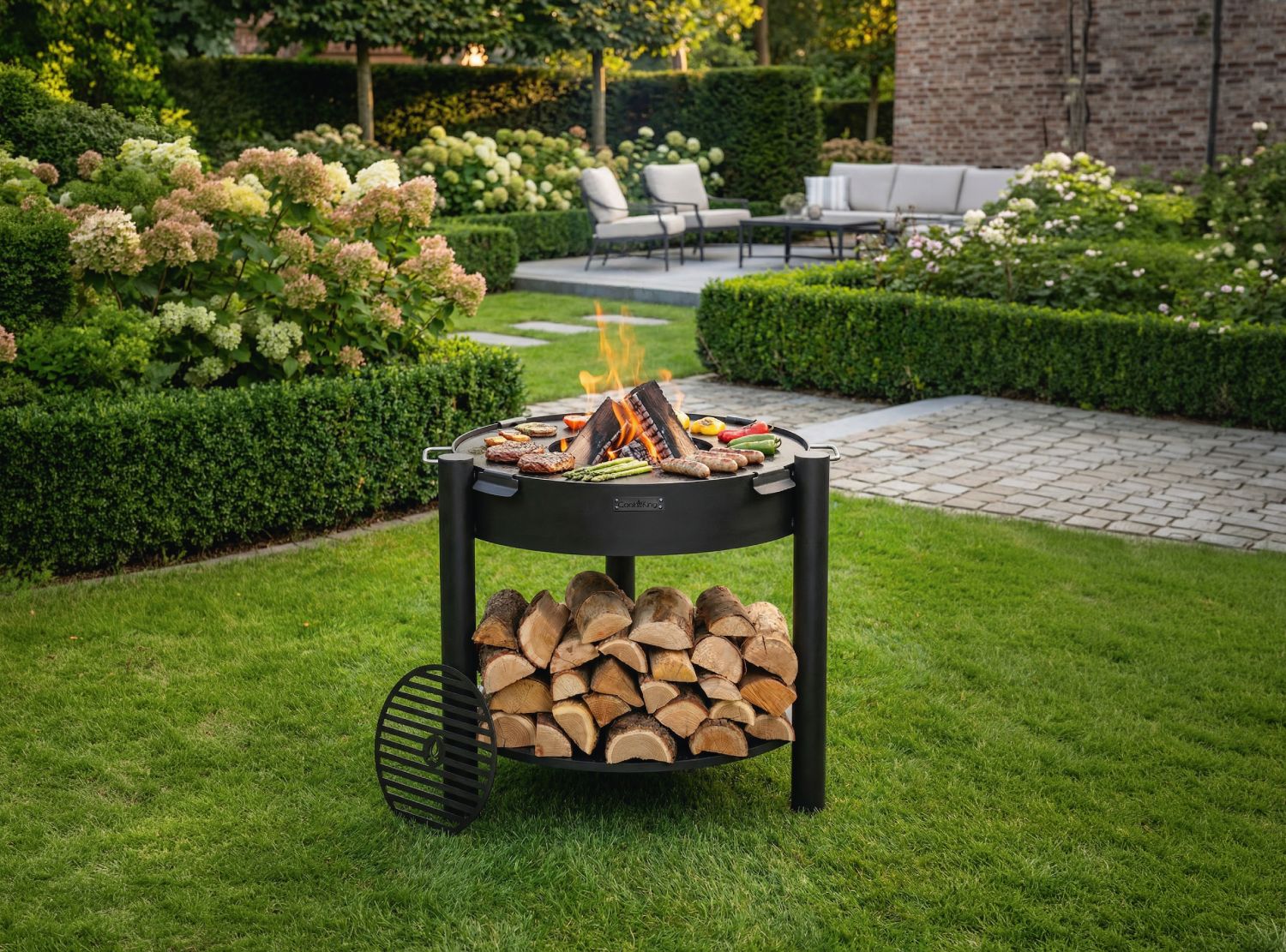 Feuerschale CookKing Montana hoch 80 cm mit Grillplatte 78 cm und Grillrost 37 cm im Garten, Naturstahl Feuerstelle mit Holzablage und Grillfunktion in Nutzung
