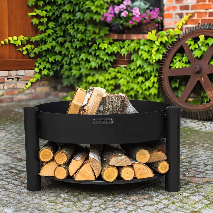 Feuerschale CookKing Montana – Feuerschale mit Holzscheiten und gefüllter Holzablage im Garten