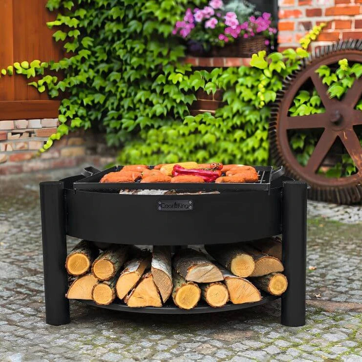 Feuerschale CookKing Montana – Feuerschale mit Grillgut und gefüllter Holzablage im Garten