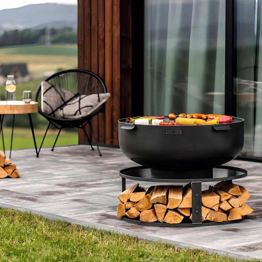 Feuerschale CookKing XXL PALERMO – Feuerschale mit Grillplatte und gefüllter Holzablage auf einer Terrasse