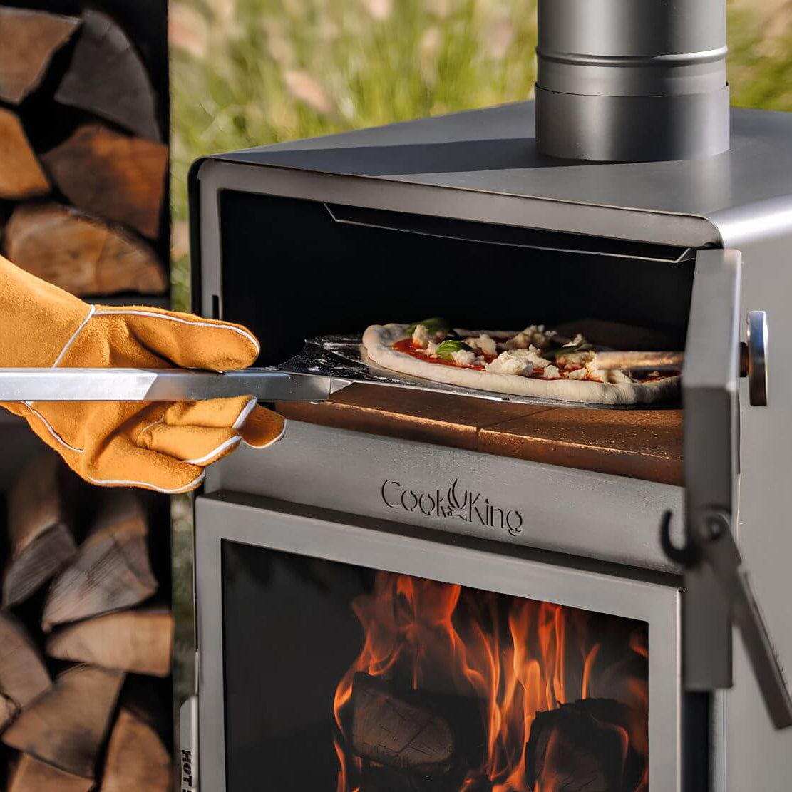 CookKing Gartenofen Vento mit Backfach – Pizza wird mit einer Schaufel aus dem geöffneten Backfach genommen