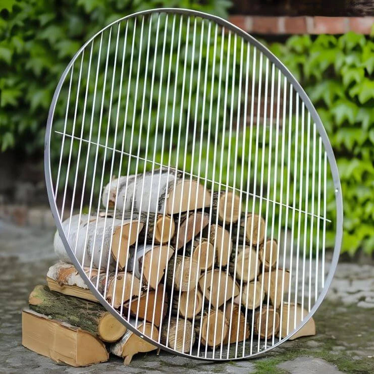 Runder Grillrost aus Edelstahl – Runder Grillrost an Holzscheiten angelehnt im Garten