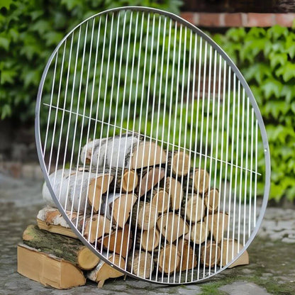 Runder Grillrost aus Edelstahl – Runder Grillrost an Holzscheiten angelehnt im Garten
