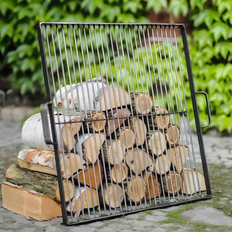 Quadratischer CookKing Grillrost aus Naturstahl an Holzscheiten vor grünen Pflanzen