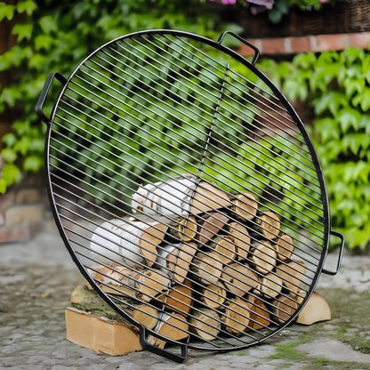 Runder CookKing Grillrost aus Naturstahl mit vier Griffen an Holzscheiten vor Grünpflanzen