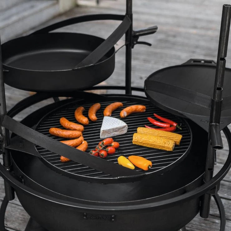 Pfanne aus Naturstahl mit Griff – Detail von Pfanne, Grillrost und Grillgut über einer Feuerschale