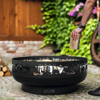 Feuerschale CookKing Forest 80 cm – Einlegen eines Holzscheits in die Feuerschale im Garten