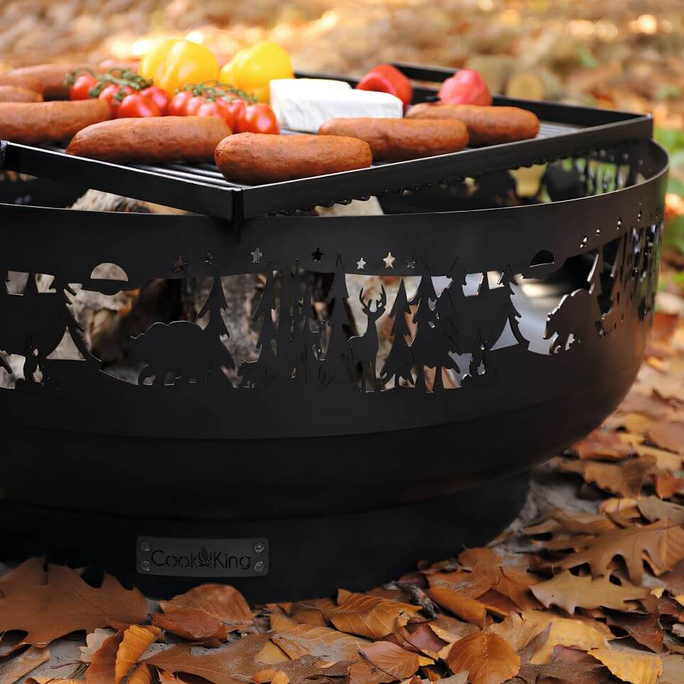 Feuerschale CookKing Forest 80 cm – Nahansicht von Grillrost, Grillgut und Schalenwand mit Waldmotiven