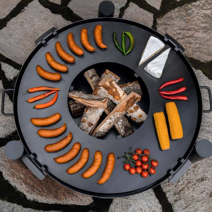 Feuerschale CookKing Haiti – Draufsicht auf die runde Grillplatte mit Grillgut und Holzscheiten