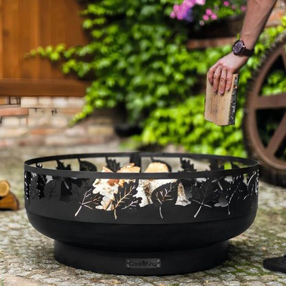 Feuerschale CookKing Toronto 80 cm – Einlegen eines Holzscheits in die Feuerschale im Garten