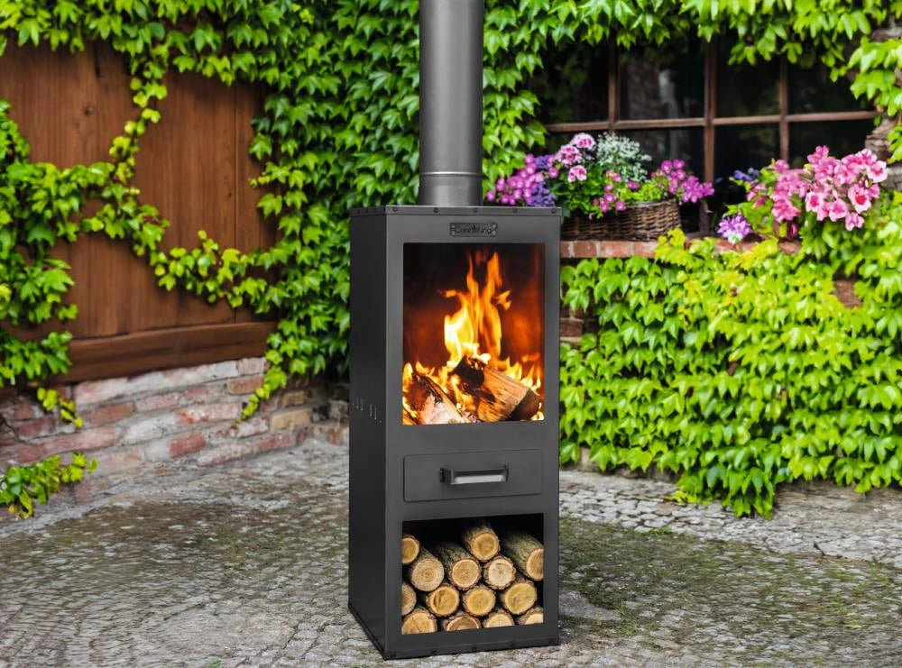 CookKing Gartenofen Rosa mit Flammen und gefülltem Holzfach vor Gartenblumen