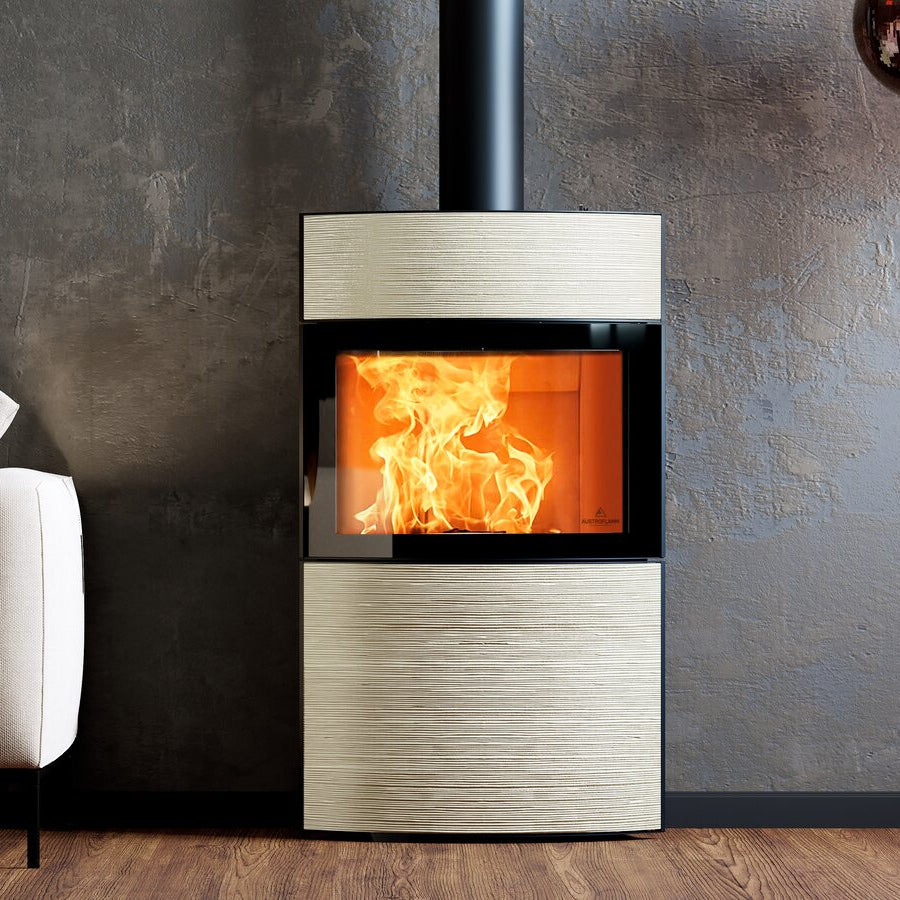Kaminofen Austroflamm Fynn Xtra 2.0 | 6 kW – im Wohnraum, Frontansicht mit gerillter heller Keramik und sichtbarem Feuer