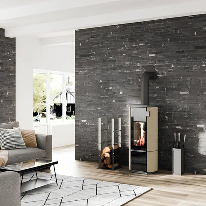 Kaminofen CERA DESIGN Conte mini rund | 5 kW – Runder Kaminofen vor einer dunklen Steinwand im Wohnraum