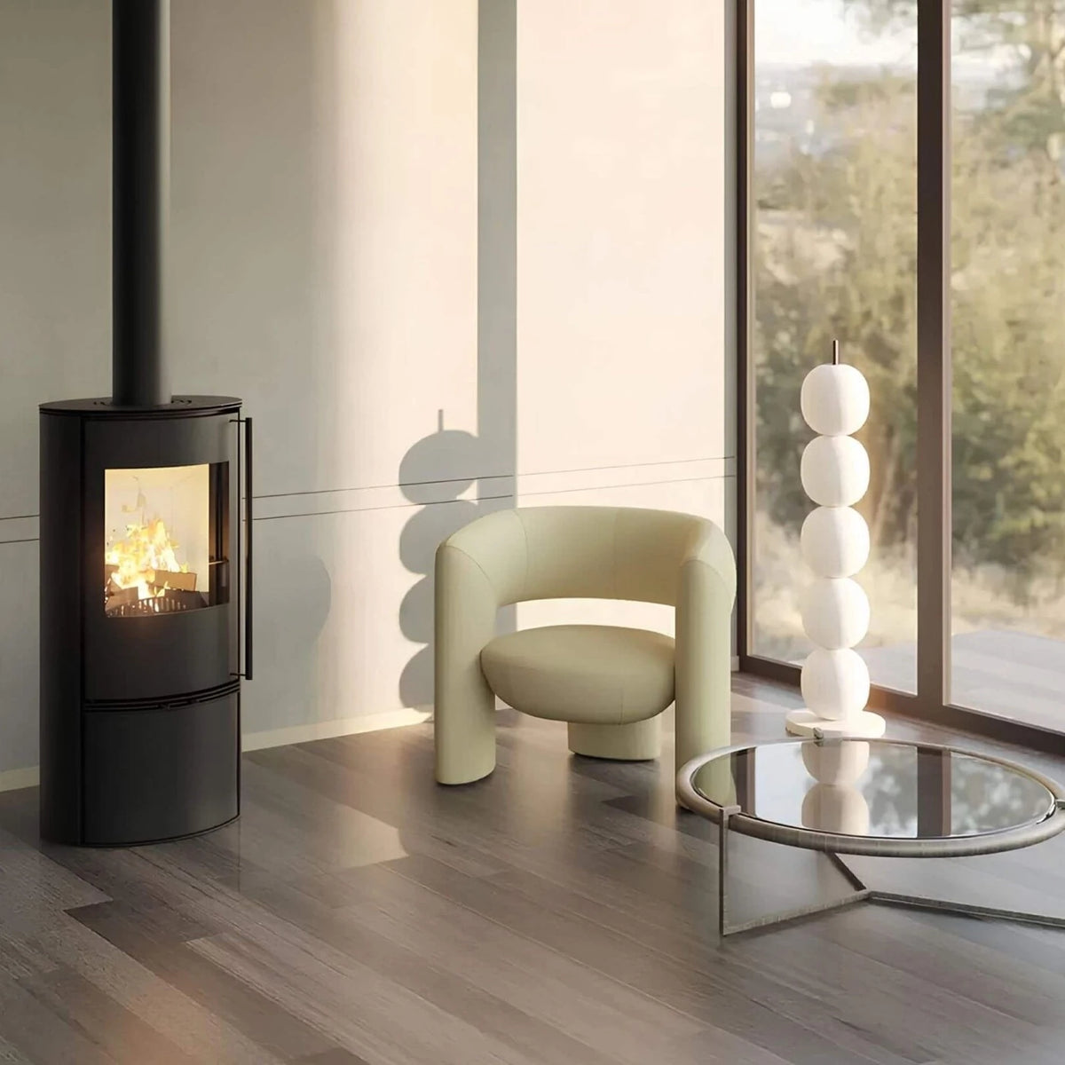 Kaminofen Hitze Bane 5 kW – Runder Kaminofen mit Feuer neben einem Sessel und Glastisch