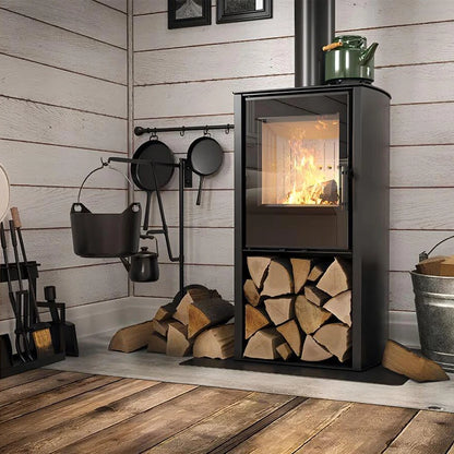 Kaminofen Hitze Cane S 6,5 kW – Dunkler Kaminofen mit Feuer und gefülltem Holzfach vor einer Holzwand