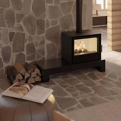 Kaminofen Hitze CF700V | 8,5 kW – Kaminofen mit Feuer auf einer Bank vor einer Natursteinwand