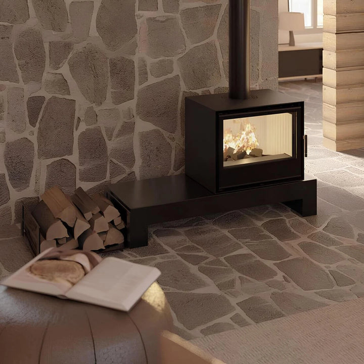 Kaminofen Hitze CF700V | 8,5 kW – Kaminofen mit Feuer auf einer Bank vor einer Natursteinwand