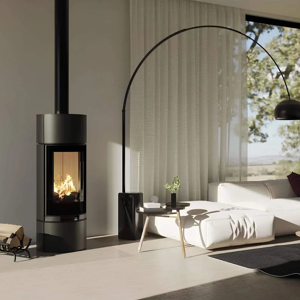 Kaminofen Hitze Charuto 8,5 kW – Hoher runder Kaminofen mit Feuer neben Sofa und Bogenlampe