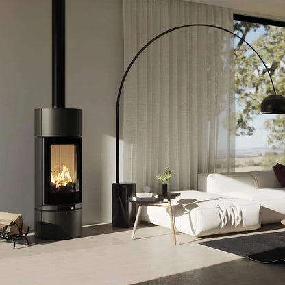 Kaminofen Hitze Charuto 8,5 kW – Hoher runder Kaminofen mit Feuer neben Sofa und Bogenlampe
