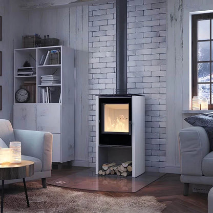 Kaminofen Hitze Lupo S 6,5 kW – Kaminofen mit weißen Seiten, Feuer und Holzfach vor einer hellen Ziegelwand