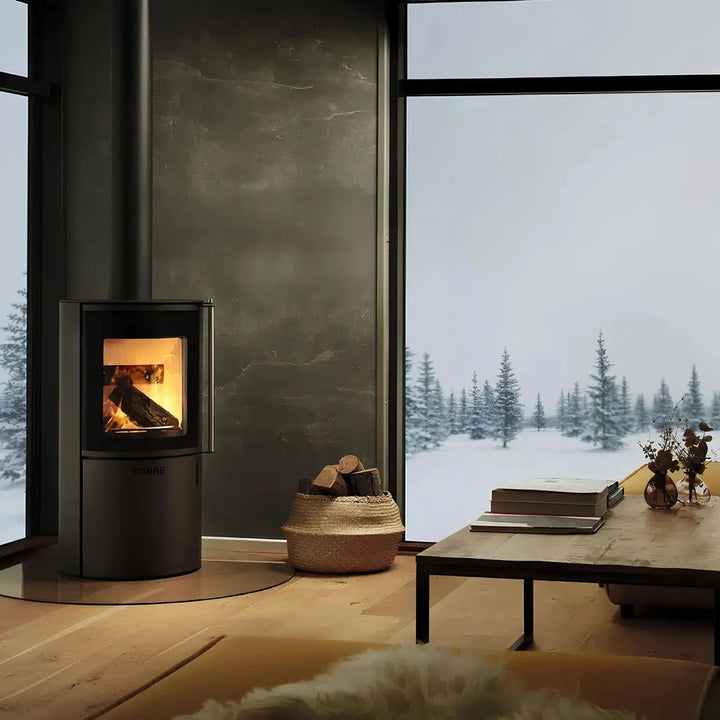 Kaminofen Varde Ovne Nordic 3 | 5 kW – Kaminofen mit Feuer vor einer Fensterfront mit Schneelandschaft