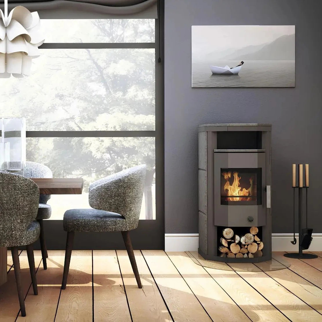 Dauerbrandofen Wamsler Thyra DB mit Automatik | 6 kW – Kaminofen neben einer Sitzgruppe am großen Fenster