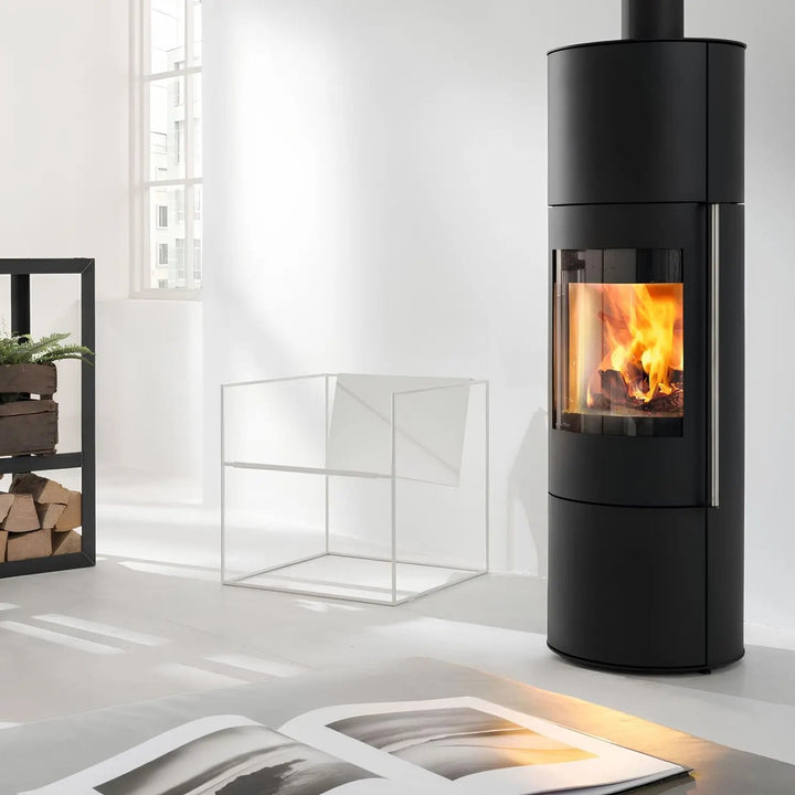 Kaminofen Wodtke Porto Largo | 5 kW – Hoher runder Kaminofen mit Feuer in einem hellen Wohnraum