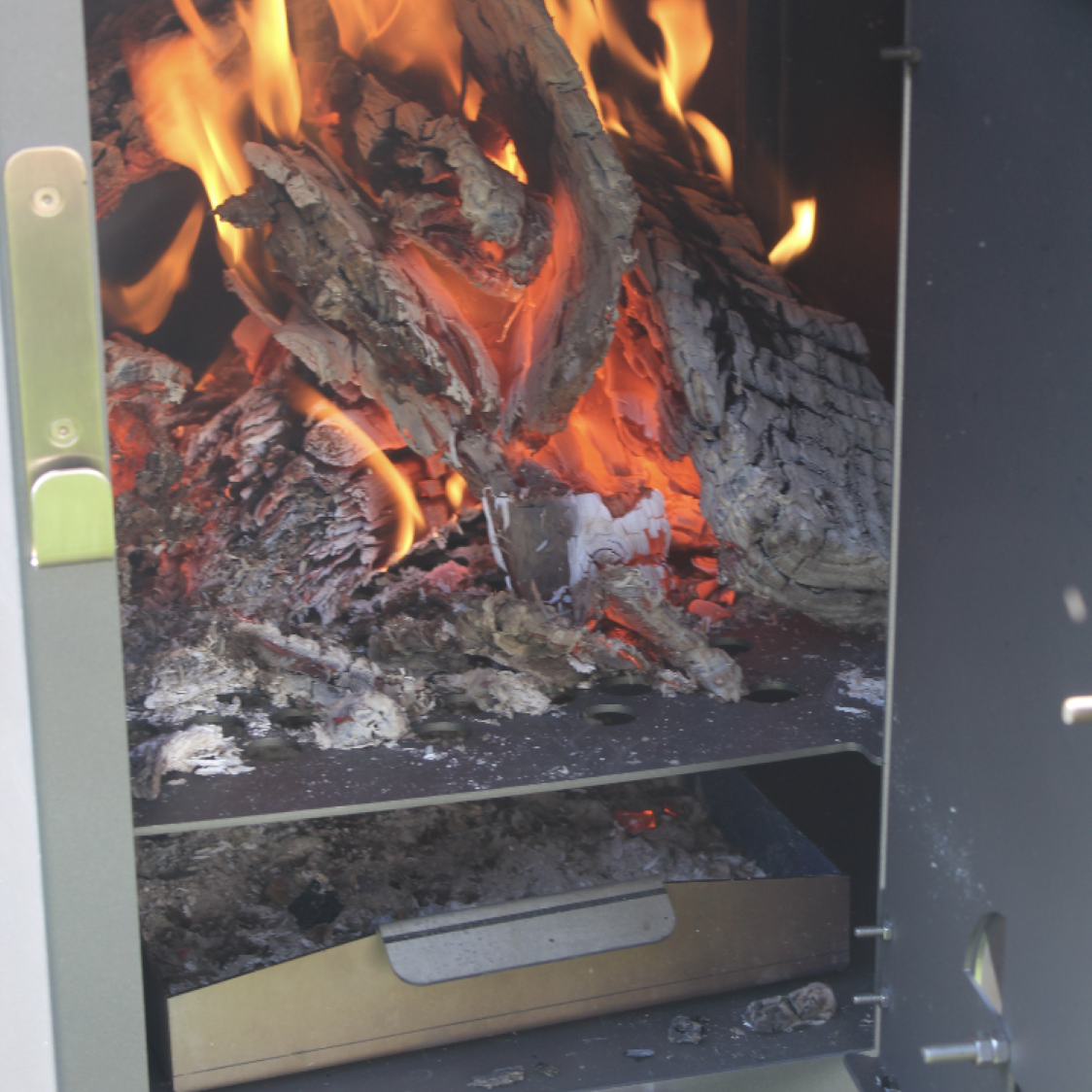 Outdoor-Ofen Stehtisch aus Edelstahl Ø 120 cm mit Sichtfenster – Blick in die brennende Feuerkammer