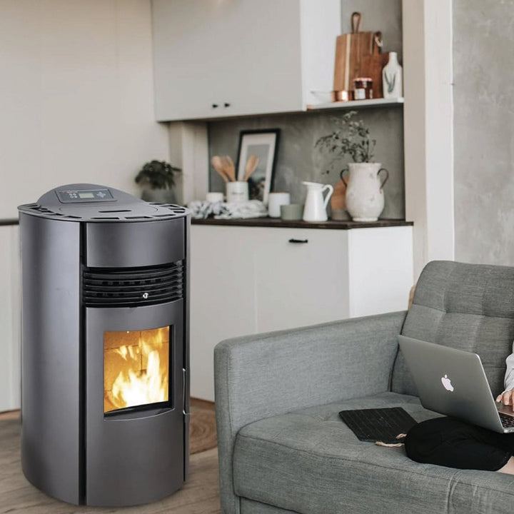 Pelletofen SCHENGER HP51-R | 8,8 kW – Runder Pelletofen mit Feuer neben einem Sofa