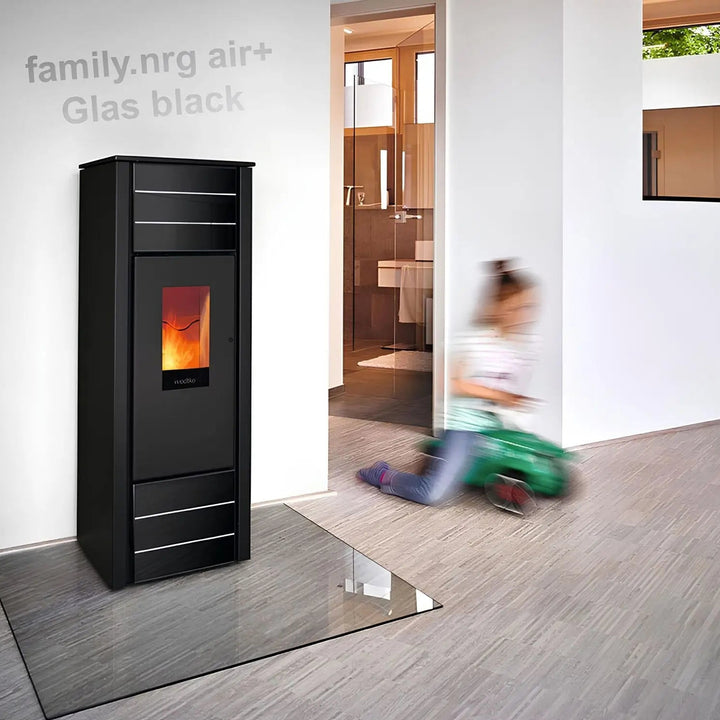 Pelletofen Wodtke family.nrg air+ | 6/8 kW – Schwarzer Pelletofen auf einer Glasbodenplatte im Wohnraum