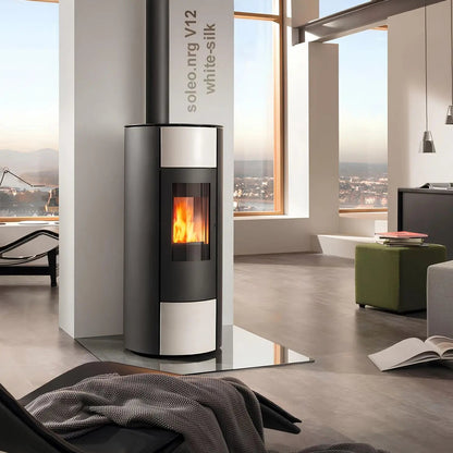 Pelletofen Wodtke soleo.nrg V12 air+ | 6/8 kW – Runder Pelletofen mit heller Verkleidung auf einer Glasplatte im Wohnraum