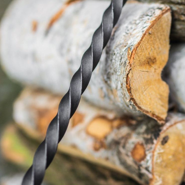 Schürhaken für Feuerschale und Funkenfang – Detail des gedrehten Schafts vor Holzscheiten