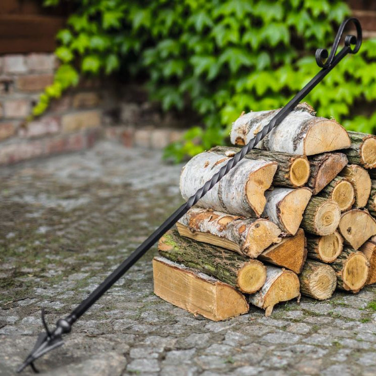 Schürhaken für Feuerschale und Funkenfang – Schürhaken an einem Holzstapel im Garten
