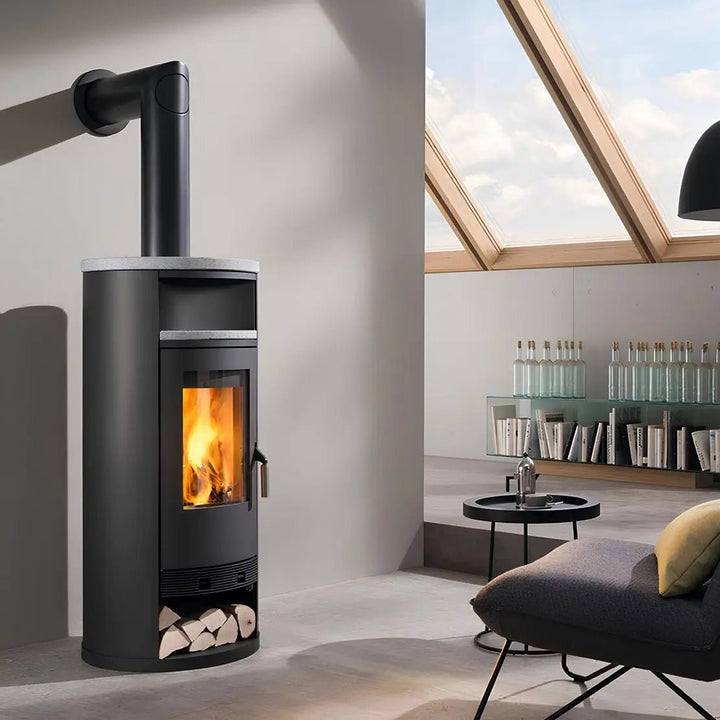 Wasserführender Kaminofen Wodtke Momo water+ | 8 kW – Runder Kaminofen mit Rauchrohr und Holzfach unter Dachfenstern